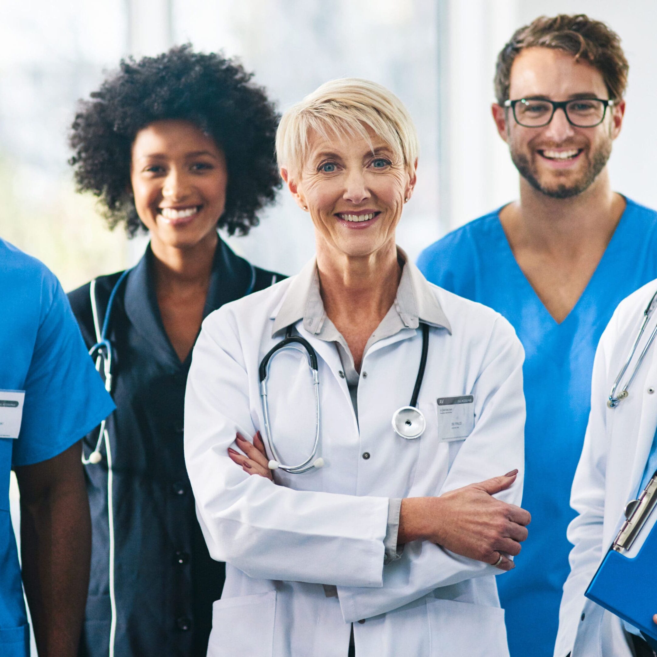 Smiling diverse healthcare professionals in uniforms standing together.