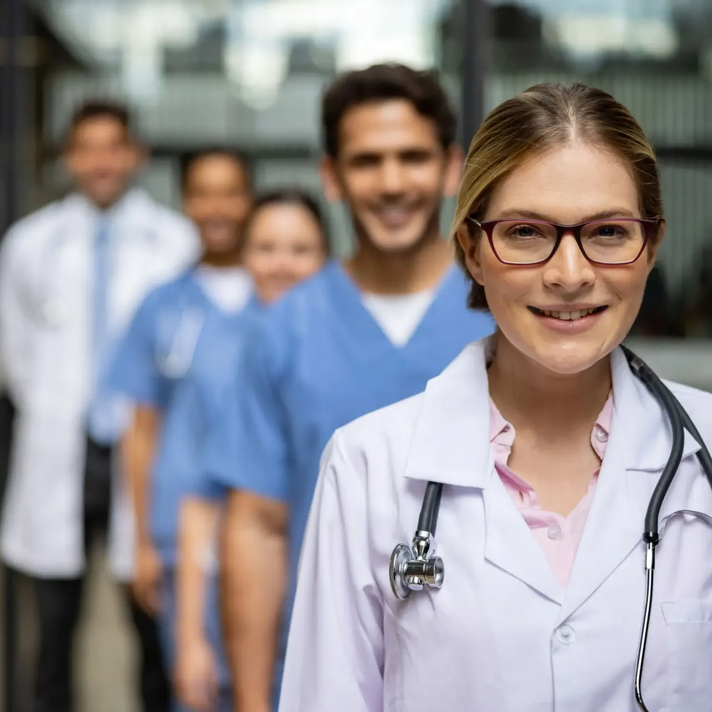 Smiling female doctor with healthcare team in hospital corridor.